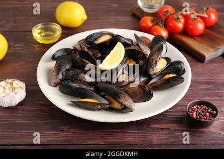 Plate of tasty mussels on wooden background Stock Photo