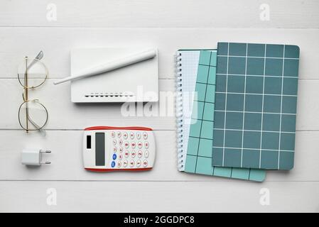 Composition with modern wi-fi router, stationery and calculator on white wooden background Stock Photo