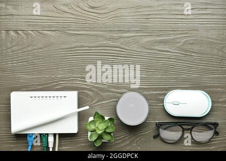 Composition with wi-fi router, PC mouse, speaker and glasses on wooden background Stock Photo