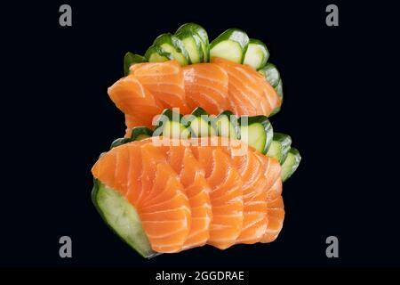 salmon sashimi and slices of cucumber on black background Stock Photo