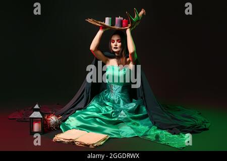 Young witch performing ritual on dark background Stock Photo