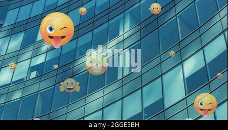 Image of emoji icons flying up over modern office building Stock Photo