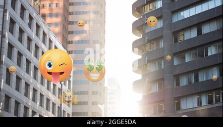 Image of emoji icons flying up over modern office buildings Stock Photo