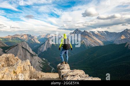 Hiker standing on a rock, mountain landscape with river valley and peaks, peak with orange sulphur deposits, Overturn Mountain, panoramic view Stock Photo