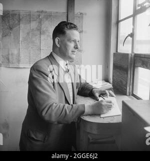 A view of William R. Bowdren, a Laing Checker, working at the Portishead 'B' Power Station site. A cropped version of this image was published in the 'People' section of the May 1957 edition of Laing's monthly newsletter, Team Spirit. Portishead B Power Station opened in the mid 1950’s. Portishead's original power station, which was completed in 1929, became known as Power Station 'A'. Portishead B was built on part of the Great Western Railway’s original Portishead Railway Station, which was demolished and rebuilt closer to the centre. Portishead B had eight coal-fired and four Stock Photo