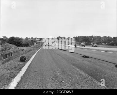 A general view looking north on the Stafford By-pass during the construction of the Birmingham to Preston Motorway (M6), showing a B type structure in the foreground and a Fc type structure in the background (bridges) with asphalt surfacing in progress on the west carriageway. Work on the Stafford By-pass started in September 1960 and was opened to traffic in December 1962.