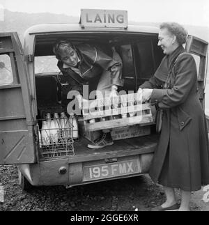 A man and woman loading a van with crates of food and drink from the canteen at the headquarters of the London to Yorkshire Motorway project, for staff working on Section B of the project. The first 53 miles of the M1, the London to Yorkshire Motorway, opened in November 1959 and spanned from Berrygrove in Hertfordshire (Junction 5) to Crick in Northamptonshire (Junction 18). Work on this section was coordinated from the project headquarters in Newport Pagnell. Stock Photo