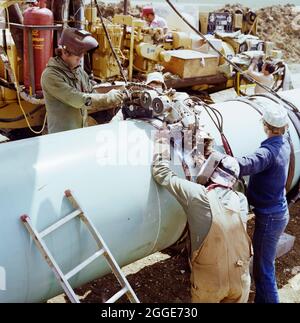 A team of welders working on the Martin pipeline, operating an automatic 'hot pass' welding bug. The Martin gas pipeline was installed in 1981 by Laing Industrial Engineering and Construction Ltd for British Gas. Running 84km from Hatton in Lincolnshire to Peterborough, it crossed 50 roads, eight rivers and four railways. Laing's site headquarters was at Martin in Lincolnshire. Stock Photo
