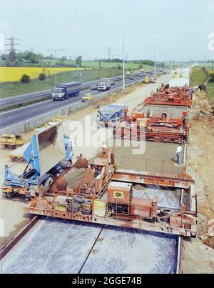 Slipform paving machines laying a road surface during widening works on the M1, showing concrete being tipped into the machine in the foreground. Starting in 1981, widening work was carried out on the M1 between Junctions 5 (South Watford) and Junction 8 (Hemel Hempstead). The aim was to convert the existing two-lane carriageways from Junctions 5 - 7 and three lane carriageways from Junctions 7 - 8 into three lanes southbound, three lanes northbound from Junctions5 - 6, and four lanes northbound from Junctions 6 - 8. Stock Photo
