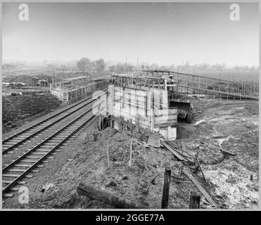 A view of the construction of the Stafford By-pass on the Birmingham to Preston Motorway (M6), looking east across the motorway towards Stafford and showing Bridge 302 being built over the main Stafford-Wolverhampton railway. The work on the Stafford By-pass started in June 1960 and was opened to traffic in August 1962.