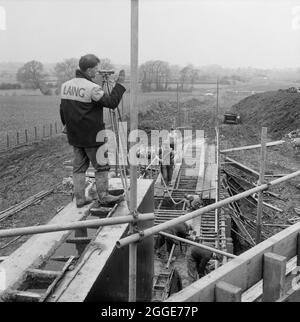 A Laing worker carrying out surveying during the construction of the Stafford/Wolverhampton railway bridge (Bridge 302) on Section A of the Birmingham to Preston Motorway (M6). The work on the Birmingham to Preston Motorway (M6), between junctions J13 to J16 started in June 1960 and was carried out by John Laing Construction Ltd. Section A was 51/4 miles in length between Dunston and Whitgreave. This bridge is located at grid reference SJ9253218880. Stock Photo