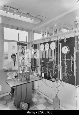A man working in a laboratory containing pressure gauges at Harp Lager Brewery. The new brewery for Harp Lager at Manor Park was built by Laing with the design of the project being carried out by architects and engineers from the Group Technical Services, working with engineers from Arthur Guinness, Son and Company Limited. John Laing Construction Ltd began the building work in 1961 and the brewery was opened in 1963. The brewery was taken over by Bass in 1979, then later by Molson Coors, subsequently closing in 2015. Stock Photo