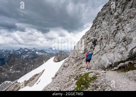 Two female hikers, mountaineer on a path with remnants of snow, mountain panorama, dramatic cloudy sky, Heilbronner Weg, Allgaeu Alps, Allgaeu Stock Photo