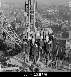 The team of Laing workers who worked on dismantling a tower crane posed for a photo on the roof of a tower, possibly Cromwell Tower, on the Barbican construction site. A cropped version of this image was published in the March 1969 edition of the Laing newsletter Team Spirit. It names the Laing workers as follows from left to right: Back row; J. Williams (fitter), J. O'Keefe (crane driver), J. Steeden (in charge) and Ginger Weaving (fitter). Front row; S. O'Brian (banksman), C. Moffat (crane driver), M. Kelly (foreman scaffolder) and J. O'Shea (scaffolder). Stock Photo