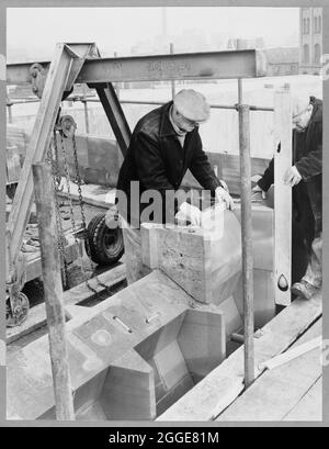 Masons fixing a section of a window sill into position during the construction of Coventry Cathedral. The caption in the album below the photograph reads &quot;...The Bronze cramps are then to tie the joints of the stone together as is normal practice.&quot; Stock Photo