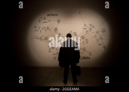 Silhouette of a man in the darkness looking at the illuminated wall with the star map Stock Photo