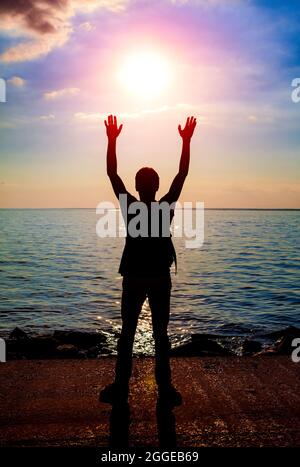 Toned Photo of Happy Person Silhouette at the Sunset on the Sea Background Stock Photo