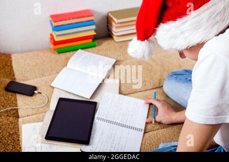Teenager in Santa's Hat doing Homework on the Couch Stock Photo
