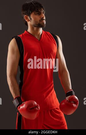 PORTRAIT OF A CONFIDENT BOXER STANDING WEARING BOXING GLOVES Stock Photo