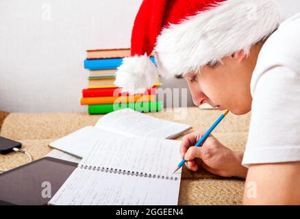 Student in Santa's Hat doing Homework on the Couch Stock Photo
