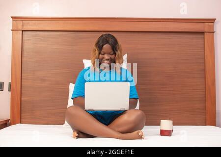 african lady working with her laptop computer while sitting in bed Stock Photo