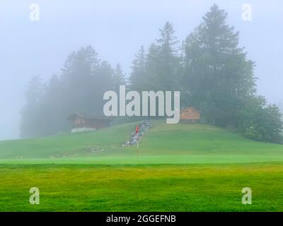 Golf Hole 18 on Crans Sur Sierre Golf Course with Fog in Crans Montana in Valais, Switzerland. Stock Photo