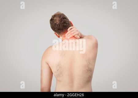 Young man is holding his neck and suffering from pain. High quality photo Stock Photo