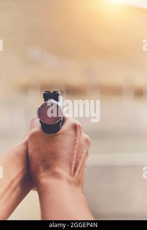 Gun in the hands of a girl, close-up arms. Stock Photo