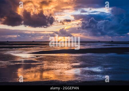 Sunset on a cloudy colorful sky over the North Sea in Denmark with high reflection in the water Stock Photo