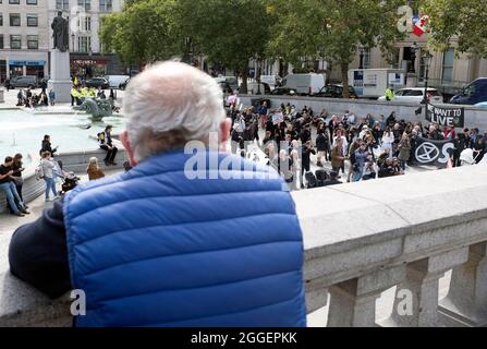 Tourist pictured watching as Extinction Rebellion protestors arrive at Trafalgar Square. Protestors have painted childrenÕs prams white and performed a slow, silent funeral from Parliament Square to Trafalgar Square on the ninth day of their Impossible Rebellion in London, United Kingdom on August 31, 2021. Kieran Riley/Pathos Stock Photo
