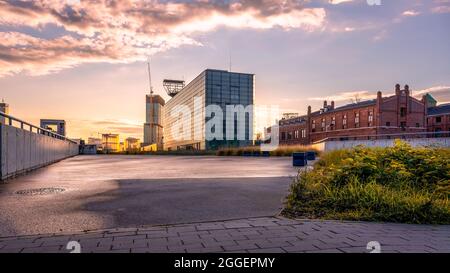 Katowice city panorama seen from a frog's perspective, the setting sun reflecting in modern glass buildings. An old coal mine converted into a public Stock Photo