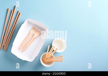 Paper cups, dishes, bag, wooden forks, drinking straws, fast food containers, wooden cutlery on light blue background. Eco craft paper tableware. Recy Stock Photo