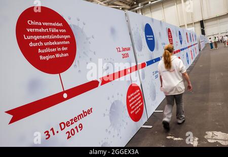 Hamburg, Germany. 31st Aug, 2021. An employee walks past a timeline with some dates of the Corona pandemic on the last day of opening at the vaccination center in the Hamburg exhibition halls. Germany's largest vaccination centre opened for the last time on Tuesday. After that, the facility, which most recently administered mainly second vaccinations, will cease operations for good. In the past eight months, a good 1.16 million vaccinations were administered, according to the social services department. Credit: Christian Charisius/dpa/Alamy Live News