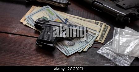 Cocaine plastic packets, guns and US dollars banknotes on a table. Drugs narcotics illegal business concept. White powder addiction and crime Stock Photo