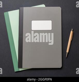 School notebooks old fashioned and a pen on black color background, top view. Back to school, supplies and accessories Stock Photo