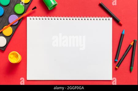 Creative kids, painting and drawing. Colorful paints and brushes on red color background, empty blank paper, copy space, template. Education, Back to Stock Photo