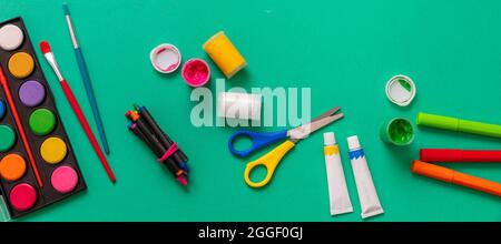 Creative kids, painting and drawing. Colorful paints and brushes on green color background. Education, Back to School concept. Stock Photo