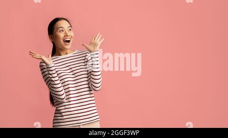 Surprised Young Korean Lady Raising Hands And Looking At Copy Space With Excitement, Amazed Asian Woman Emotionally Reacting To Nice Offer Or Promo, S Stock Photo