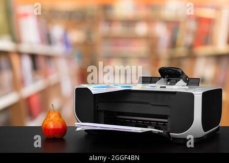 Compact laser printer on black desk against blurred background Stock Photo