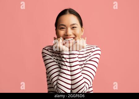 Portrait Of Cute Young Asian Woman Touching Face And Looking At Camera With Excitement, Pleased Korean Female Emotionally Reacting To Nice Offer Or Sa Stock Photo