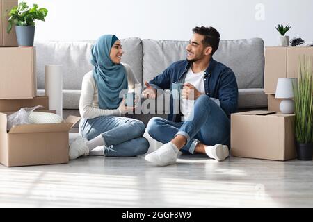 Positive middle-eastern family drinking coffee while unpacking Stock