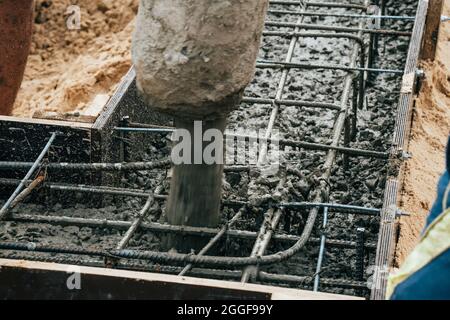 Pouring cement or concrete with automatic pump, construction site with reinforced grillage foundation, start of new house building construction. Stock Photo