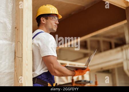 Male worker using laptop at house building construction site Stock Photo