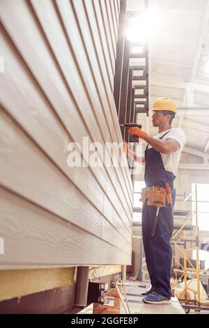 Male builder using cordless electric drill at construction site Stock Photo