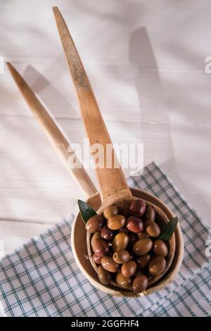 Presentation of a small group of black olives on wooden ladle Stock Photo