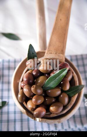 Presentation of a small group of black olives on wooden ladle Stock Photo