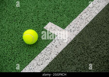 A tennis ball by the baseline on a green hard surface tennis court Stock Photo