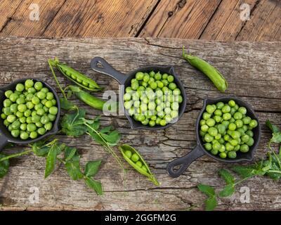 Fresh green peas young in bowls, on wood table, top view, seeds, pods, sprouts Stock Photo