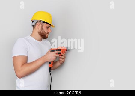 Man worker is drilling a hole on the wall for construction or renovation. High quality photo Stock Photo