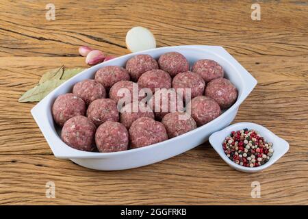 Raw meat balls on a white plate with seasonings. Stock Photo